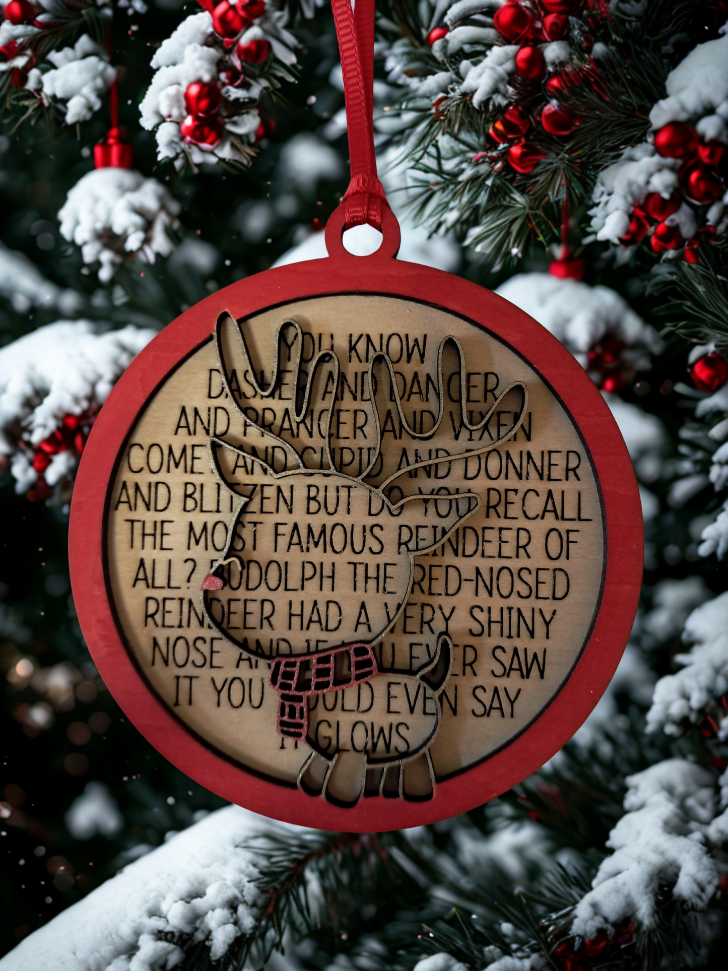 A festive reindeer ornament featuring a classic holiday poem. Perfect for decorating your Christmas tree. Measures 4 inches across and comes with a ribbon hanger. Back layer is engraved with: You know Dasher and Dancer and Comet and Cupid and Donner and Blitzen, but do you recall the most famous reindeer of all? Ruduloph the Red-nosed Reindeer had a very shiny nose, and if you ever saw it, you would even say it glows.