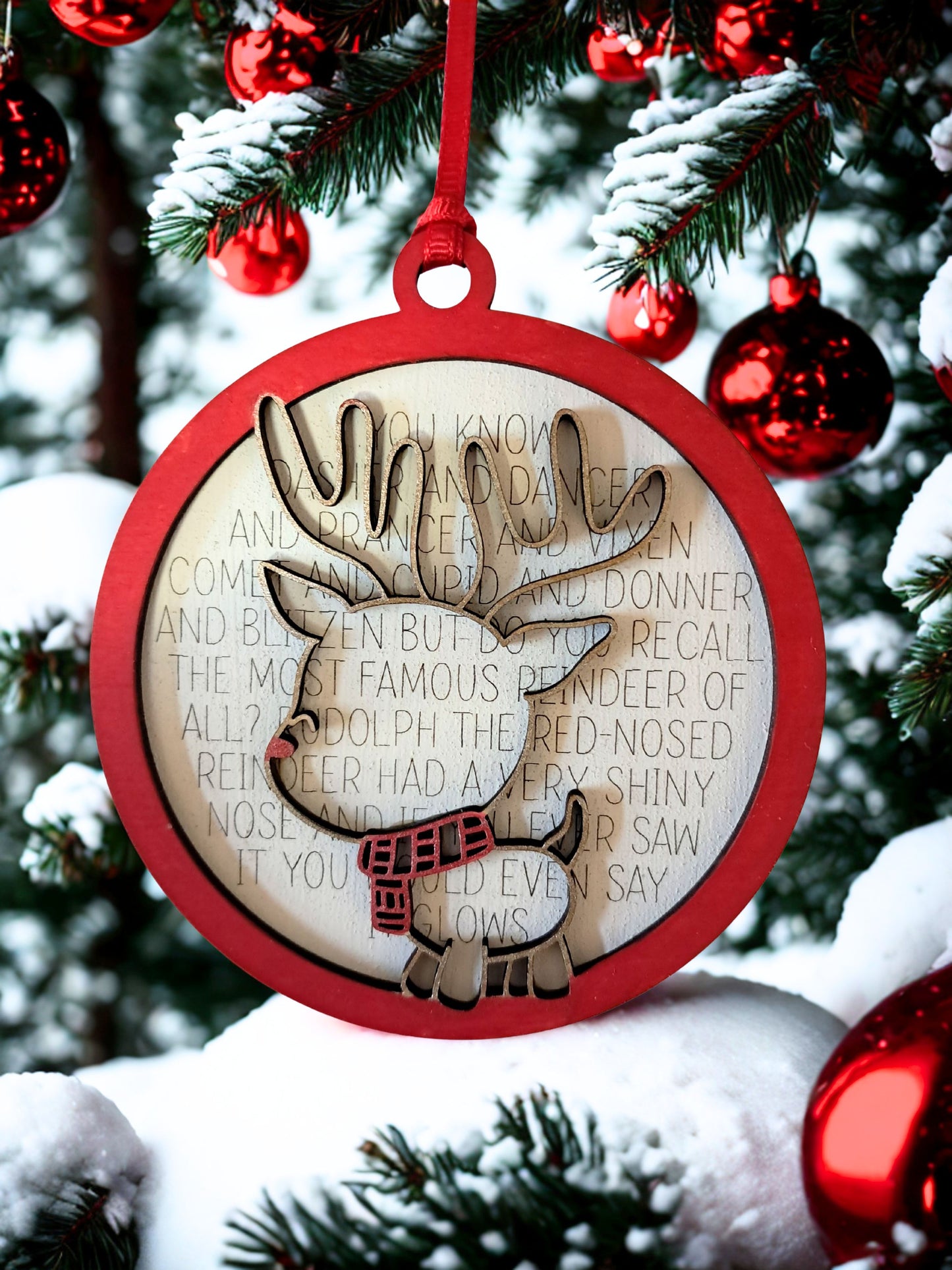 A festive reindeer ornament featuring a classic holiday poem. Perfect for decorating your Christmas tree. Measures 4 inches across and comes with a ribbon hanger. Back layer is engraved with: You know Dasher and Dancer and Comet and Cupid and Donner and Blitzen, but do you recall the most famous reindeer of all? Ruduloph the Red-nosed Reindeer had a very shiny nose, and if you ever saw it, you would even say it glows.